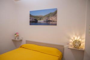 a bedroom with a yellow bed and a painting on the wall at Il Mirto Residence in Marina di Camerota