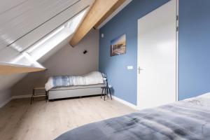 een slaapkamer met blauwe muren en een bed en een raam bij Chezeehoeve - Wemeldinge in Wemeldinge