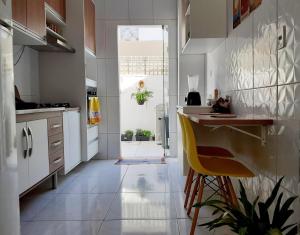 a kitchen with white cabinets and a yellow chair at Casa Arembepe in Camaçari