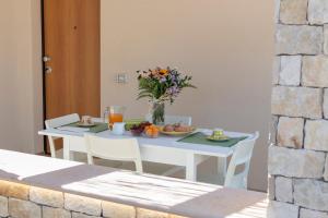 a white table with a vase of flowers on it at Il Mirto Residence in Marina di Camerota