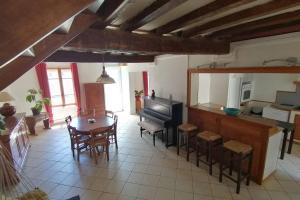 a living room with a table and a piano at Maison chaleureuse et de détente avec piscine et spa in Chassemy