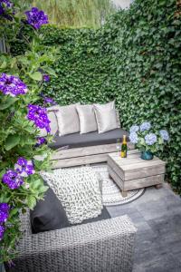 a couch sitting on a patio with purple flowers at Petite Maison Bennebroek in Bennebroek