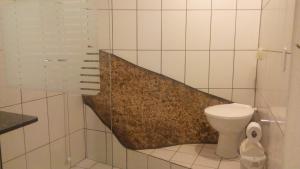 a white tiled bathroom with a sink and a toilet at Studio Formana in Florianópolis