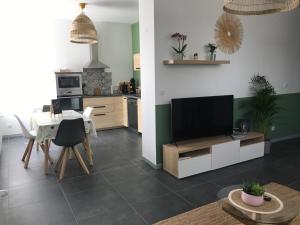 a living room with a television and a table with chairs at Appartement au cœur du Val d'Argent in Sainte-Croix-aux-Mines