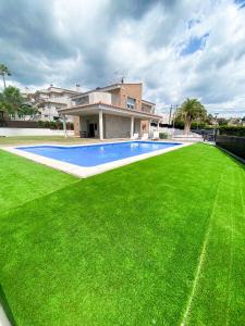 a large yard with a swimming pool in front of a house at Villa Las Palmeras in Tarragona
