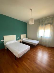 two beds in a room with green walls and wooden floors at Villa Las Palmeras in Tarragona