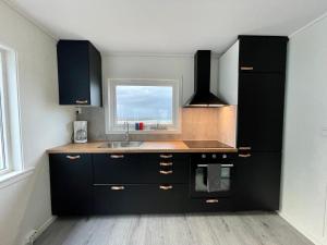 a kitchen with black cabinets and a sink and a window at Lofoten_Beach_Eggum in Eggum