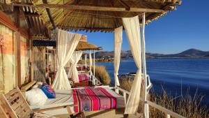 a bed in a porch with a view of the water at Titicaca Aruntawi Lodge Peru in Puno