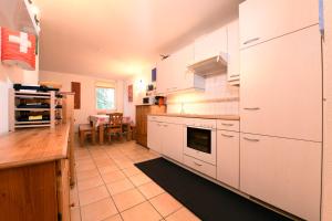 a large kitchen with white cabinets and a table at Bosco Gurin Nature & Ski in Bosco Gurin