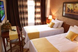 um quarto de hotel com duas camas e uma mesa em Hotel el Hayat em Batna