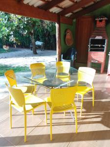 una mesa de cristal y sillas amarillas en el patio en Casa Verde en Pirenópolis