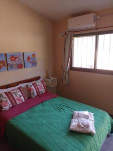a bedroom with a green bed and a window at Complejo Los Gringos in Villa Ciudad de America