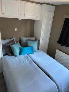 a large white bed with blue pillows in a bedroom at Luxe Chalet 146 in Putten +10 photos
