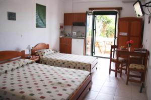 sypialnia z 2 łóżkami i biurkiem oraz kuchnia w obiekcie Evon's Rooms w mieście Fanari +37 zdjęć