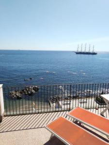 un balcone con vista sull'oceano e su una nave di Appartamento con terrazzo sul mare Teocle a Giardini Naxos