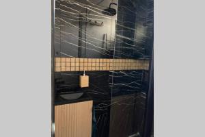 La salle de bains est pourvue de murs en marbre noir et d'un lavabo. dans l'établissement Studio COSY et confortable aux PORTES DE PARIS!, à Saint-Denis
