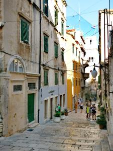an alley in an old town with people walking down it at L&L Rooms Royal in Šibenik