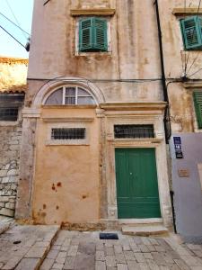 a building with a green door and two windows at L&L Rooms Royal in Šibenik