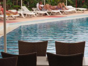 a group of people sitting on lounge chairs near a swimming pool at Cathrin Hotel in Faliraki