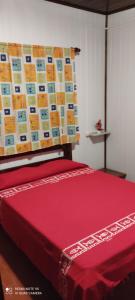 Una cama con una manta roja encima. en Los Abuelos, en La Coronilla