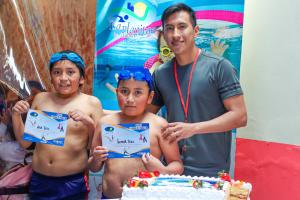 a man and two boys holding up a piece of cake at Hostal y Complejo Recreacional La Playita de Monse in Otavalo