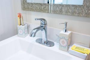 a bathroom sink with a faucet and a toothbrush holder at One Bedroom Apartment with SD Downtown View in San Diego