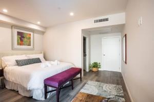 a bedroom with a large white bed with a purple bench at One Bedroom Apartment with San Diego Downtown View in San Diego