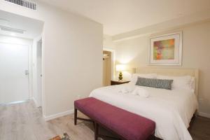 a bedroom with a large white bed with a purple bench at 1 Bedroom Apartment with Luxurious Design in SD in San Diego
