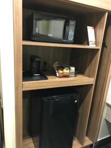 eine Mikrowelle auf einem Regal neben einem Kühlschrank in der Unterkunft Hyland Motel Brea in Brea
