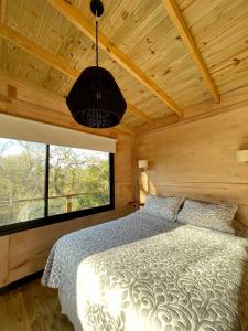 um quarto com uma cama e uma grande janela em Eco Cabaña Río - Cabaña Mirador em Tigre