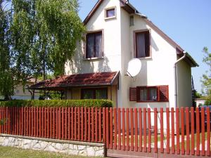 une maison avec une clôture rouge devant elle dans l'établissement Andrea apartman, à Zamárdi