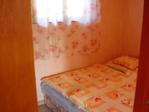 Cette petite chambre comprend un lit avec un rideau à motifs floraux. dans l'établissement Andrea apartman, à Zamárdi