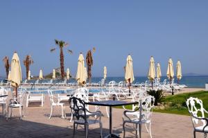 a table and chairs with umbrellas next to a pool at Royal Bay Suites in Kefalos