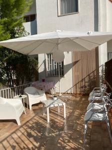 un patio con ombrellone, sedie e tavoli bianchi di Villa Italia - Marina di Lesina a Lesina