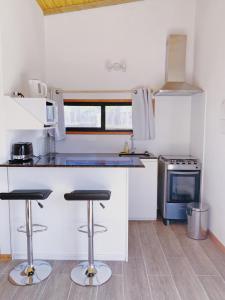 a kitchen with a counter and stools in it at Los Bungalows in José Ignacio