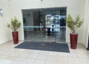 a lobby with two potted plants in front of a glass door at Apto 3 Quartos com Ar, Piscina, Garagem - Cuiabá in Cuiabá +23 photos