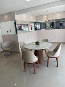 a dining room with a white table and chairs at Apto 3 Quartos com Ar, Piscina, Garagem - Cuiabá in Cuiabá