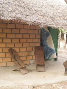 a brick building with two surfboards and a thatch roof at Kansala Ta Toto in Kafountine