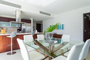 une salle à manger avec une table en verre et des chaises blanches dans l'établissement Mareazul Casa Sol norte apts, à Playa del Carmen