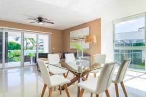 a dining room with a glass table and white chairs at Mareazul Casa Sol norte apts in Playa del Carmen