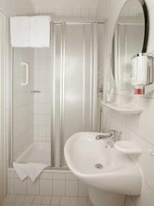 a white bathroom with a sink and a shower at Tagungshaus Schönenberg in Ellwangen