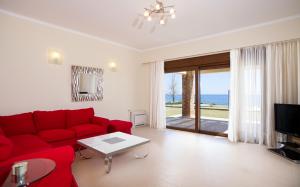 a living room with a red couch and a view of the ocean at Private beach villa Princess in Kiotari