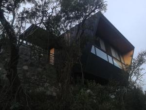 a house on top of a hill with trees at NIDO ARRIBA CABAÑAS in Villa la Bolsa