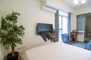 Un dormitorio con una cama y un televisor en la pared. en 馬公港精品旅宿包棟烤肉附設租車, en Magong