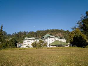 un gran edificio con un campo delante en Araliya Green Hills Hotel en Nuwara Eliya