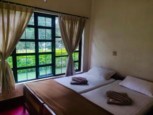 a bedroom with two beds and a large window at Dubare Inn in Madikeri