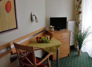 a table with a bowl of fruit and a television at Apart-Hotel Pension Roßmayer in Bad Füssing