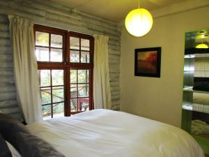 Un dormitorio con una cama grande y una ventana en Old Pine Cabin Karkloof en Karkloof Nature Reserve