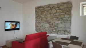 un soggiorno con una sedia rossa e un muro in pietra di B&B Al Belvedere a Volturino