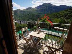 una mesa y sillas en un balcón con montañas en La Borda de Jaime, en Piedrafita de Jaca